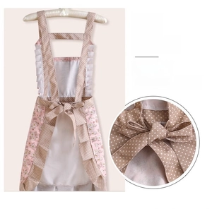 Detailed back view of floral cotton apron showing adjustable crossover straps and large bow tie