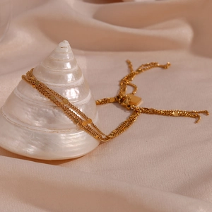 Detailed close-up of multi-layer gold sequins tassel bracelet on white shell decoration