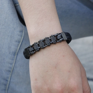 Close-up of men's punk black bike chain bracelet with braided leather on blue denim