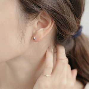 Pendiente de flor de plata S999 minimalista puesto en la oreja con acabado pulido