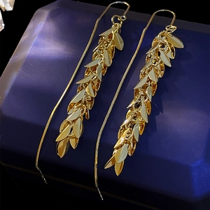 Macro detail of gold leaf tassel earrings resting on a navy jewelry box
