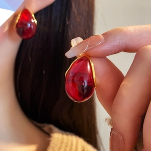 Close-up of a French style resin teardrop earring with a polished gold metal frame