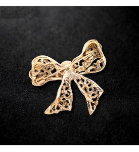 Detailed back view of a golden alloy bow brooch featuring a secure pin clasp mechanism