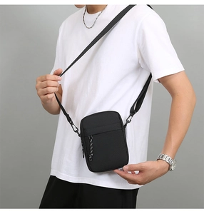 Men's black Oxford crossbody bag shown on a model with adjustable strap and woven zipper pull