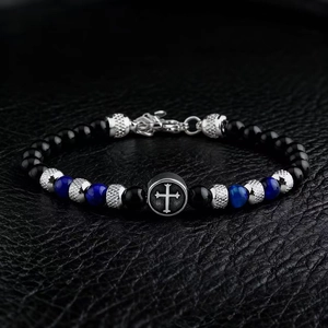 Detailed close-up of 6mm black and blue tiger eye beads with a cross charm on leather