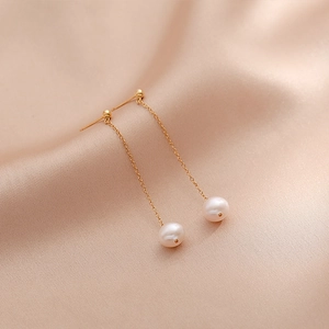 Elegant gold drop earrings with natural freshwater pearls on a champagne silk background