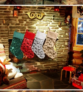 Detail of four colorful sequined Christmas stockings hanging on a vintage fireplace mantel