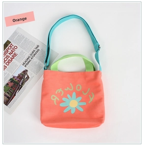 Close-up of orange canvas kids' crossbody bag with daisy print and light blue strap