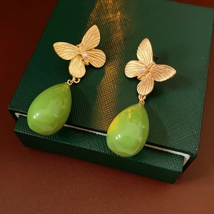 Vue macro de boucles d'oreilles papillon vintage dorées avec perles et gouttes vertes