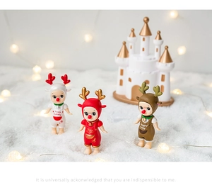Three festive reindeer figurines on snowy ground with a warm fairy light background