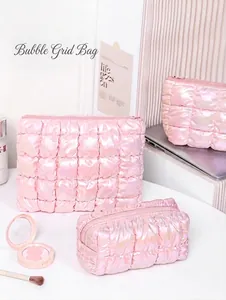 Detail of pink laser puffer cosmetic bags with quilted bubble texture on a white desk