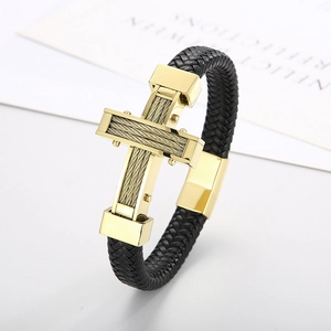 Detail of woven black leather bracelet featuring a gold steel cross and magnetic clasp