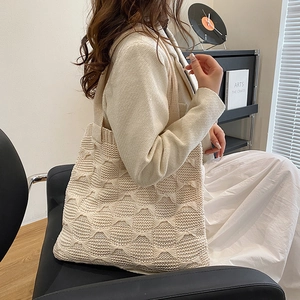 Close-up of beige knitted tote bag showing woven texture on model's shoulder