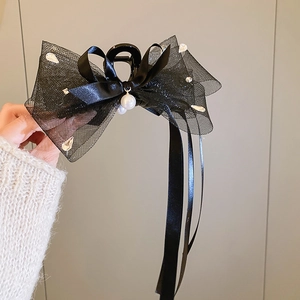 Détail de la pince à cheveux noeud en tulle noir avec rubans et perles d'imitation