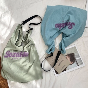 Détail du tissu gaufré et de l'imprimé lettrage violet sur les sacs cabas en toile