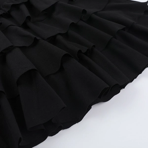 Detailed macro view showing the multi-layered ruffles and pleats of the black mini dress
