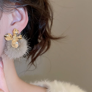 Close-up of elegant gold flower earrings with grey pom pom pendants for women