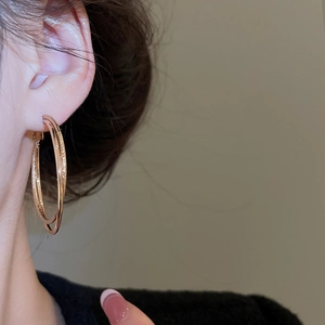 Detail of rose gold double hoop earrings with polished and frosted glitter textures