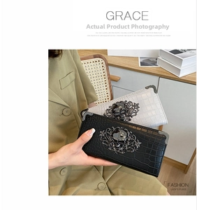Detail view of Gothic crocodile pattern clutch bag featuring 3D metal skull and floral decor