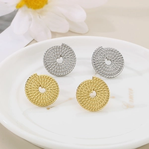 Détail de boucles d'oreilles cercle torsadées en or et argent sur un plateau en céramique