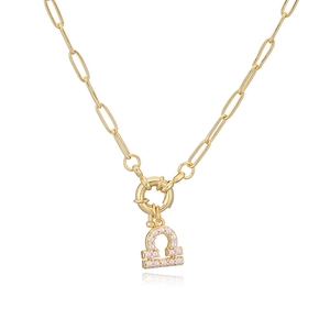 Close-up of gold Libra zodiac pendant with white pearl on paperclip chain necklace