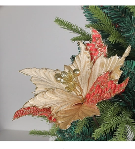 Detailed close-up of red and gold glitter Christmas flower on a green tree branch