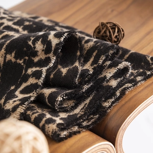Classic leopard print faux cashmere scarf in brown and black on a warm wooden bench
