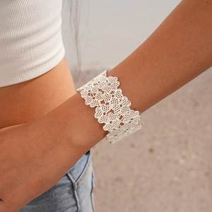 Detail view of a wide silver hollow floral cuff bracelet worn on a woman's wrist