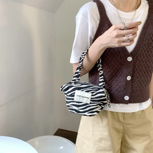 Close-up of zebra pattern knitted handbag with LOVE SOZAKKA label held by a model