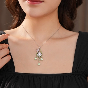 Dettaglio della collana argentata con pendente a farfalla e fiore e pietre verdi