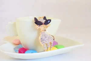 Close-up of golden cat keychain with sparkling rhinestones and black eyes on white plate