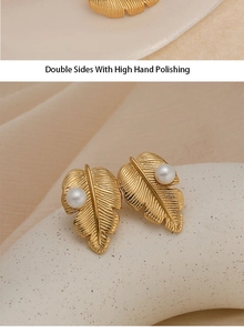Détail d'une boucle d'oreille feuille en or avec perle et texture polie à la main