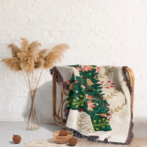 Detail of Christmas tree woven throw blanket with colorful tassels on a rattan chair