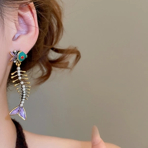 Macro shot of unique fishbone earrings with pearls and colorful enamel on a model