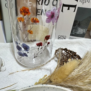 Close-up of vibrant ink flower stickers on a clear glass bottle in a cozy setting