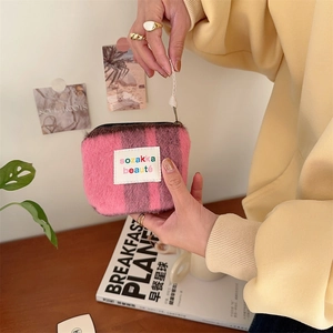 Close-up of pink fuzzy mohair stripe cosmetic bag with sozakka beaute label detail