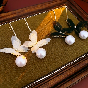 Detailed view of butterfly mesh earrings with pearls and crystals on green fabric