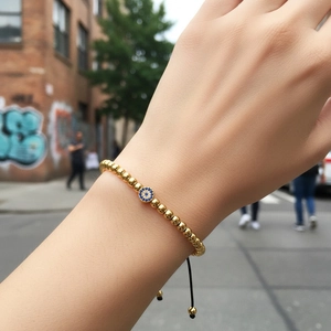 Golden beads bracelet with blue evil eye zircon charm on adjustable black cord strap