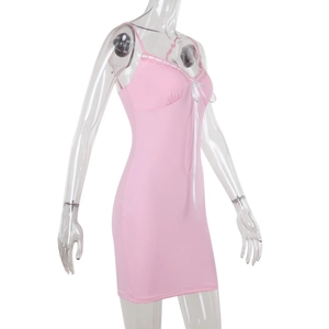 Dettaglio dell'abito aderente rosa con bordo in pizzo bianco e fiocco sullo scollo