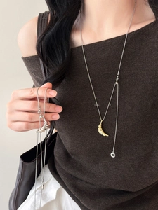 Detail of croissant pendant necklace in gold and silver finish with spiral texture