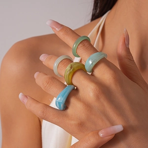 Close-up of wide acrylic resin rings in various marbled colors worn by a model