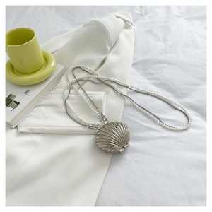 Detail of silver shell-shaped mini bag with pearl bead chain and metal strap