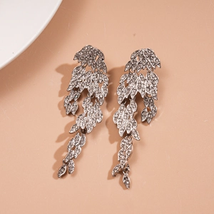 Detail of silver tassel earrings with crystal rhinestones and leaf design on peach background