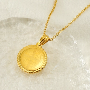 Détail du pendentif médaille de Saint-Benoît doré avec relief sur support en verre
