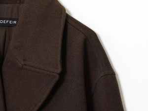 Détail d'un manteau en laine marron foncé montrant le revers, le tissu et l'étiquette de cou