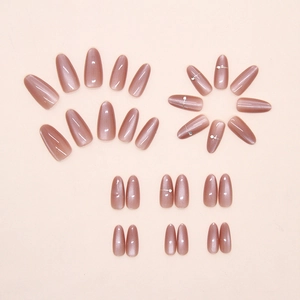 Detail of pink almond press-on nails with cat-eye glitter effect and rhinestone accents