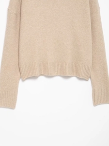 Détail de l'ourlet et des poignets côtelés sur un pull en maille beige à col montant