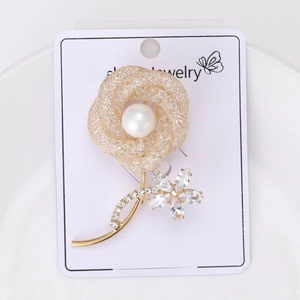 Detail of elegant gold hollow rose brooch featuring a central pearl and sparkling crystals
