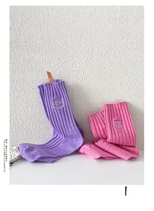 Détail de chaussettes en maille côtelée violettes et roses avec étiquette carrée en tissu