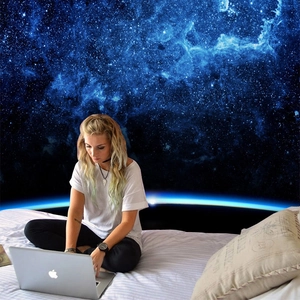 Bedroom wall decor featuring a large galaxy tapestry with deep blue nebula and stars